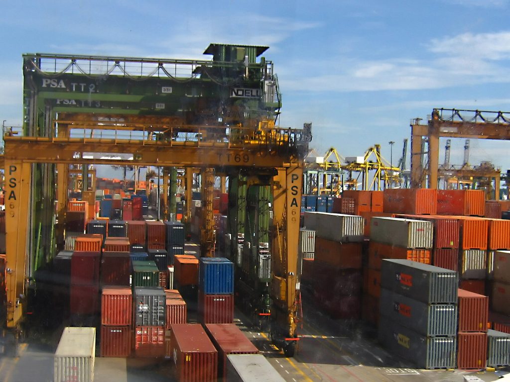 Singapore Is Building the World’s Most Automated Port, Berth by Berth Towering container cranes over a busy Singapore port terminal